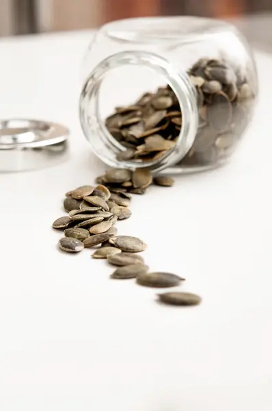 Close up of pumpkin seeds spilling out of glass jar — Stock Photo, Image