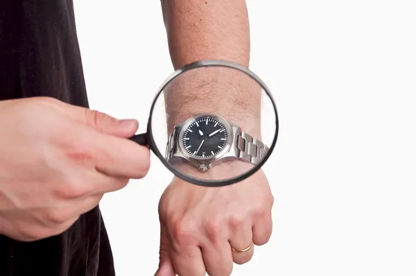 Man met vergrootglas in de hand kijken naar zijn horloge op witte backgro — Stockfoto