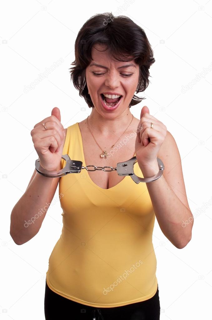 Angry young woman in handcuffs trying to free herself