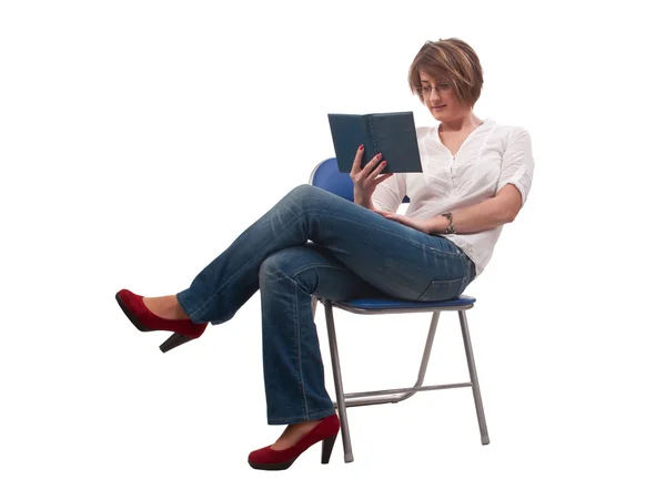 Young woman with glasses sitting on chair and reading a book — Stock Photo, Image