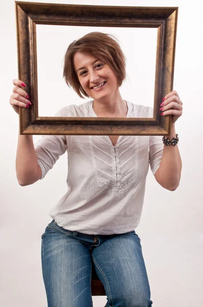 Schöne Frau hält einen Rahmen um ihr Gesicht und schaut durch — Stockfoto