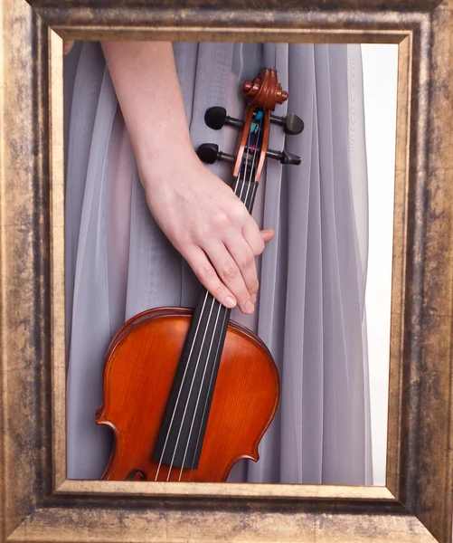 Violin i handen av en ung kvinna som sett genom en ram — Stockfoto