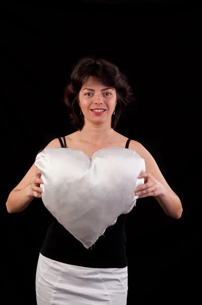 Eine schöne junge Frau mit einem weißen Herzen in der Hand — Stockfoto