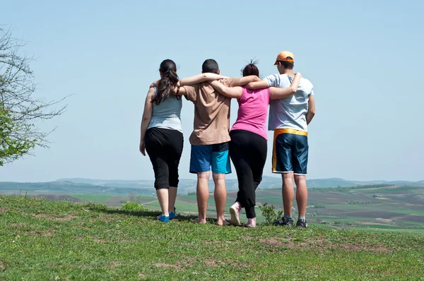 Τέσσερις happy εφηβική φίλοι αγκαλιάζοντας σε φόντο γαλάζιο του ουρανού — Φωτογραφία Αρχείου
