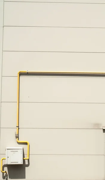 Yelow pipes and gas meter on gray wall — Stock Photo, Image