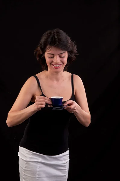 Elegant young woman holding blue cup and saucer against black ba — Stock Photo, Image