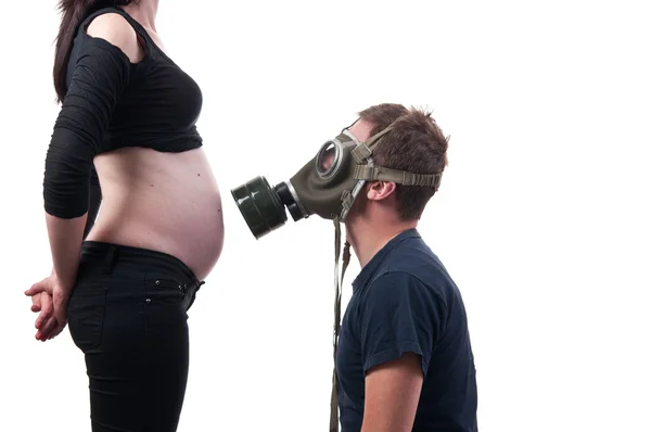 Futuro pai ficar com máscara de gás na frente da barriga de sua esposa, fumaça — Fotografia de Stock