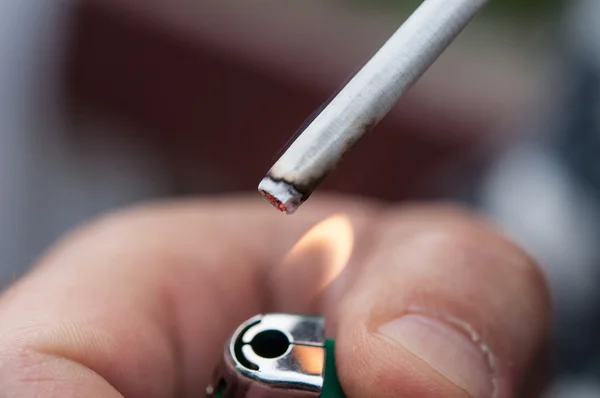 Primer plano de la mano de un hombre enciende un cigarrillo con litera — Foto de Stock