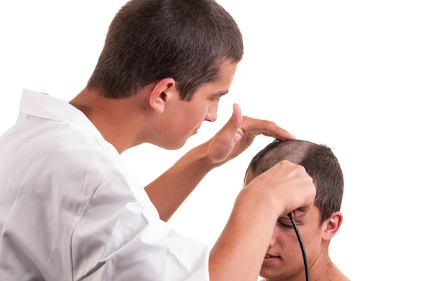 Barber cutting hair to a young man with clipper on white — Stock Photo, Image