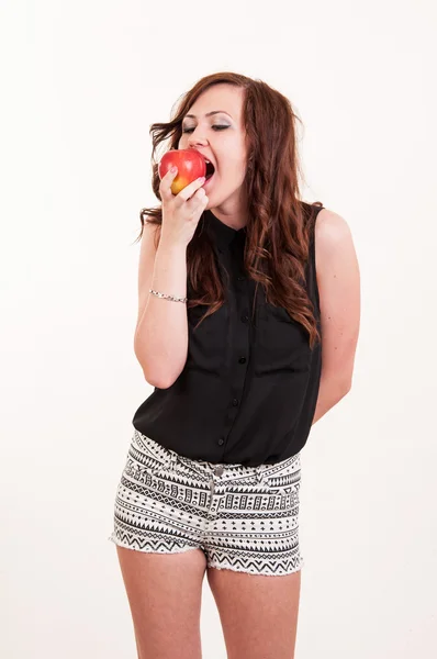 Joven hermosa mujer mordiendo una manzana roja sobre fondo blanco — Foto de Stock