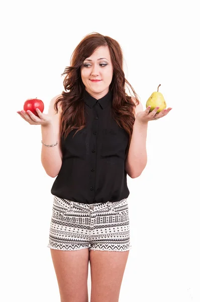 Young woman comparing an apple and a pear, trying to decide whic — Stock Photo, Image