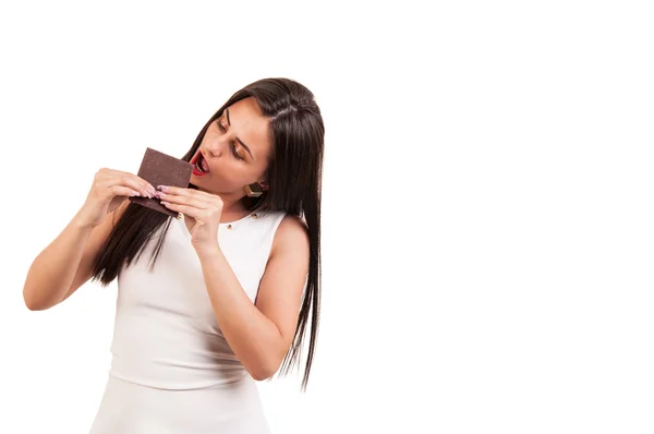 Mujer joven comiendo barra de chocolate con lujuria sobre fondo blanco , — Foto de Stock