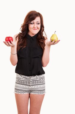 Young woman comparing an apple and a pear, trying to decide whic clipart
