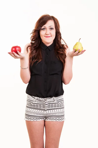 Fiatal nő összehasonlítása az alma és a körte, megpróbálja eldönteni, hogy melyik — Stock Fotó