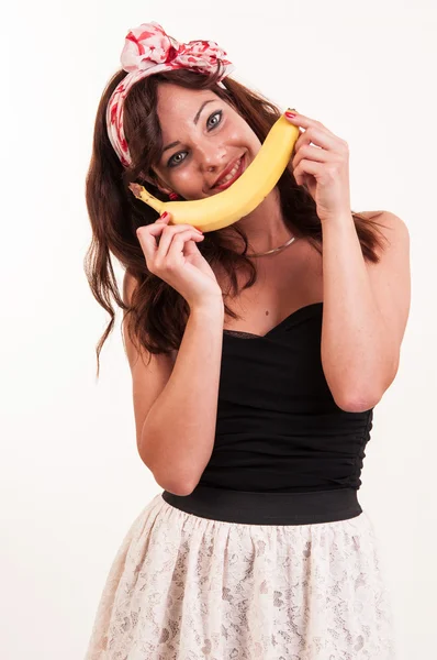 Joven mujer sostiene un plátano en su boca, imitando una sonrisa en — Foto de Stock