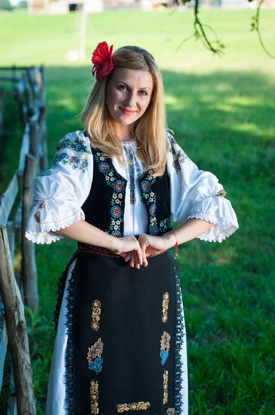 Όμορφη γυναίκα με το κόκκινο λουλούδι στα μαλλιά της, θέτουν σε ρουμανική t — Φωτογραφία Αρχείου