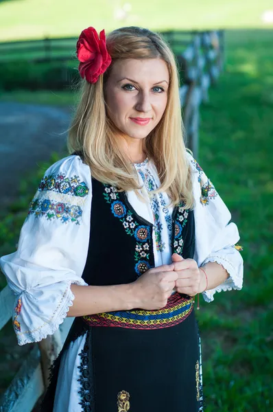 Красива жінка з Червона квітка в її волосся в Румунська t себе — стокове фото