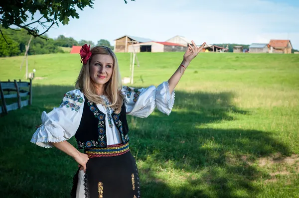 Mooie vrouw met rode bloem in het haar poseren in Roemeense t — Stockfoto