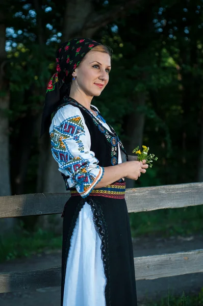 Mooie zangeres met bloemen in haar handen die zich voordeed op platteland — Stockfoto