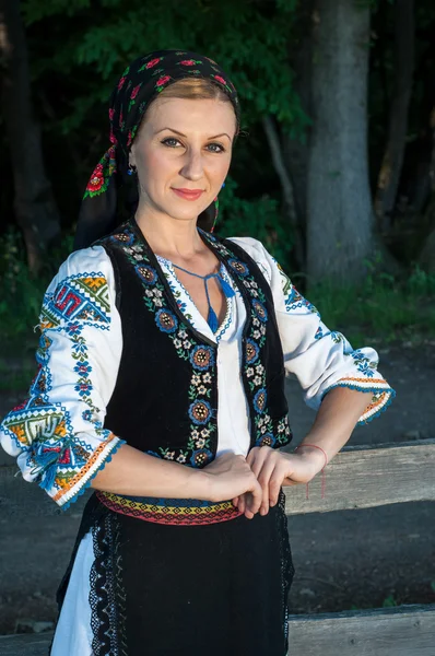 Portret van jonge mooie vrouw poseren buiten in Roemeense tra — Stockfoto