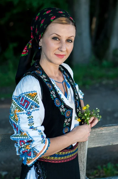 Mooie zangeres met bloemen in haar handen die zich voordeed op platteland — Stockfoto