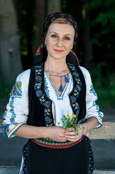 Mooie zangeres met bloemen in haar handen die zich voordeed op platteland — Stockfoto