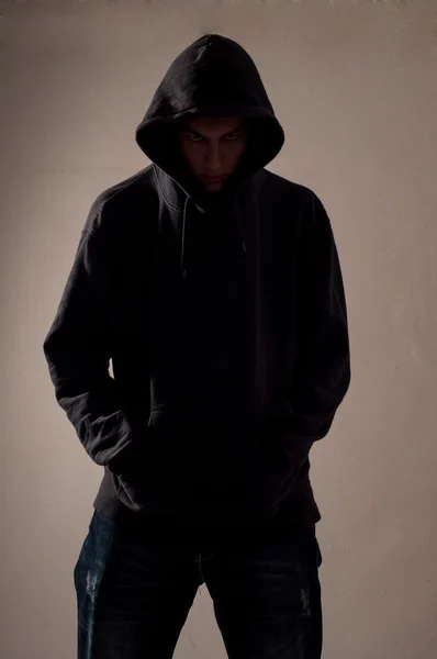 Teenager with hoodie look ahead against a dirty gray wall — Stock Photo, Image