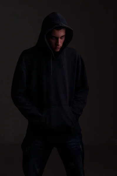 Tiener met hoodie kijken aan de ene kant tegen een vuile donker grijs — Stockfoto