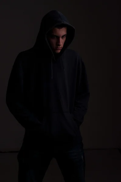 Tonåring med hoodie titta på ena sidan mot en smutsig svart vägg — Stockfoto