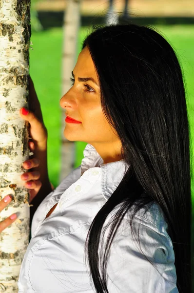 Bella giovane donna in posa vicino all'albero verde sulla natura — Foto Stock