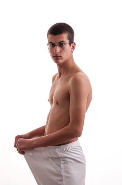 Young man showing his lost weight by putting on an old pants — Stock Photo, Image