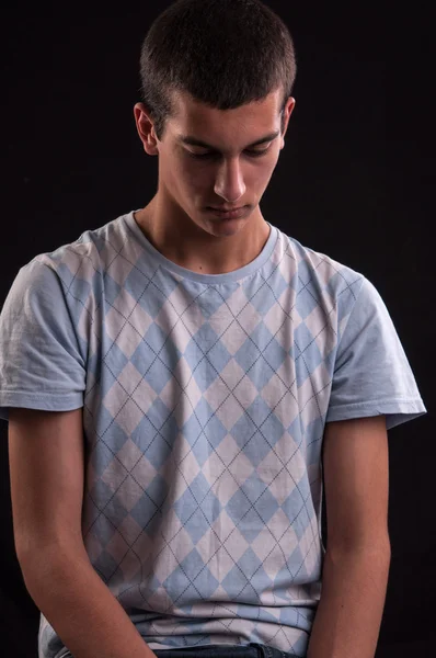 Serious and thoughtful teenage boy sits on chair, he thinks no o — Stock Photo, Image