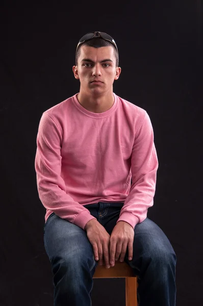 Young man with sunglasses sitting on chair — Stock Photo, Image