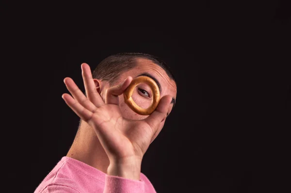 Cheerful teenager look through a bagels hole, focus on his eye — Stock Photo, Image