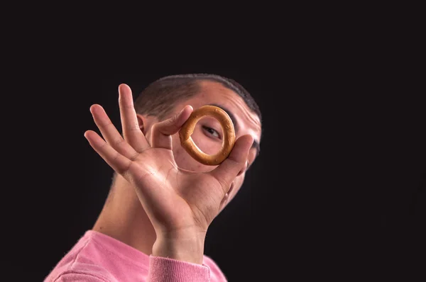 Cheerful teenager look through a bagels hole, focus on bagel — Stock Photo, Image