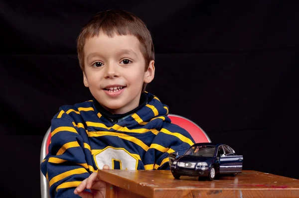 Smiling little boy plays indoor with toy car — Stock Photo, Image