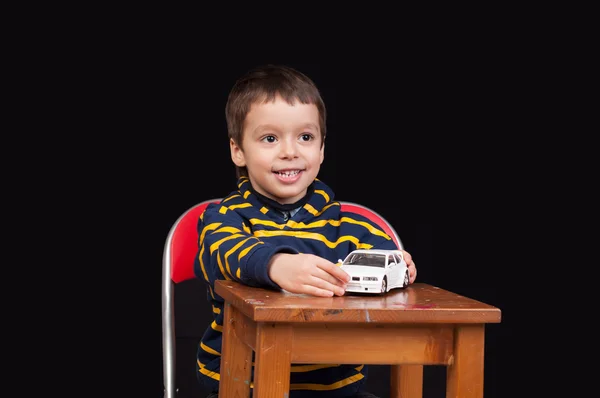 Улыбающийся мальчик играет в помещении с игрушечной машиной — стоковое фото