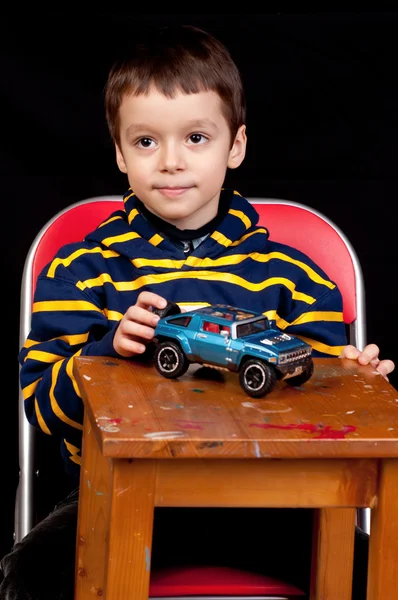Sorridente bambino gioca al coperto con auto giocattolo — Foto Stock