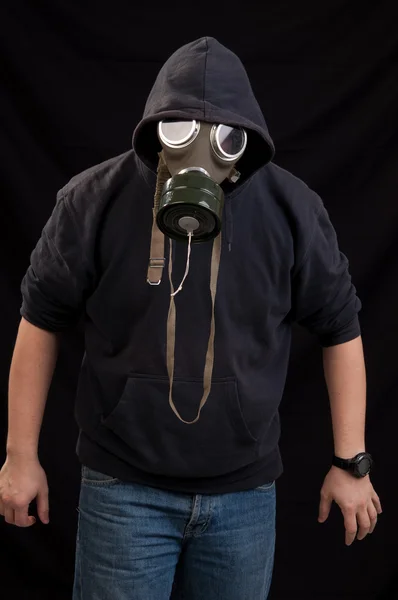 Mens in zwarte kleren dragen van een klassieke gasmasker over een donkere rug — Stockfoto