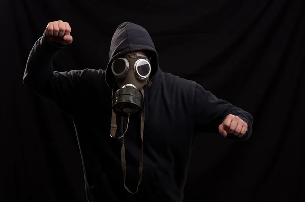 Mann in schwarzer Kleidung mit klassischer Gasmaske über dunklem Rücken — Stockfoto