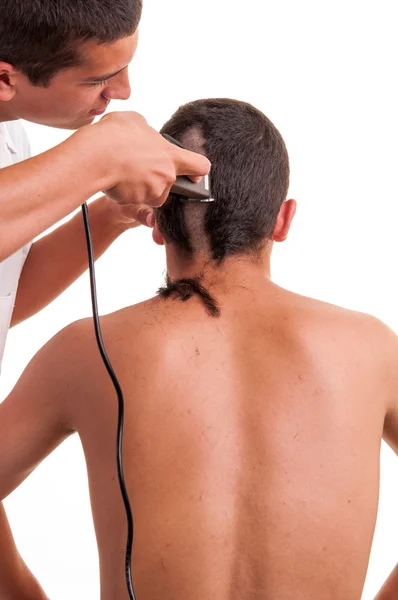 Frisör klippa hår till en ung man med clipper på vit — Stockfoto