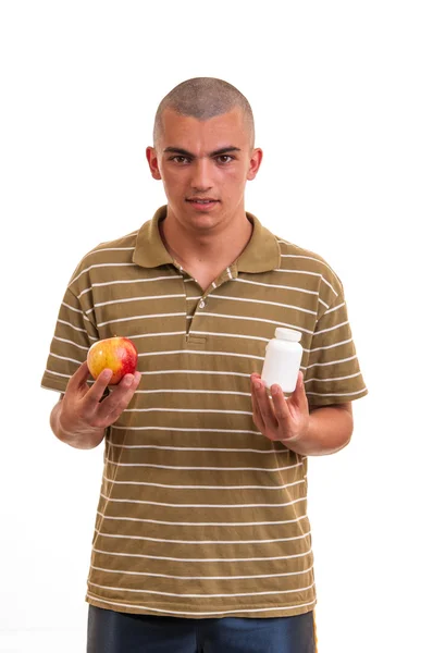 Man offering pill in one hand and apple in another. Copy space b — Stock Photo, Image