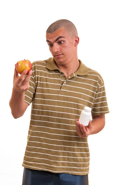 Homem oferecendo pílula em uma mão e maçã em outra. Espaço de cópia b — Fotografia de Stock