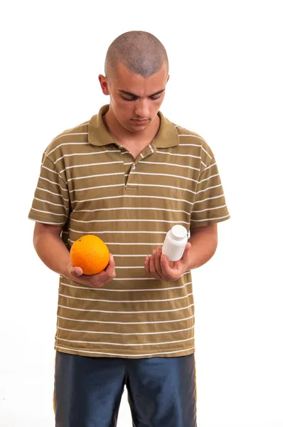 La elección correcta. joven sosteniendo una naranja en una mano y pi — Foto de Stock