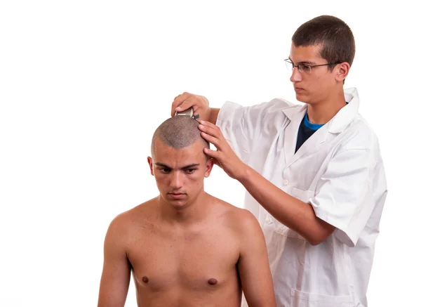 Парикмахер стрижет волосы для молодого человека с клиппером на белом — стоковое фото