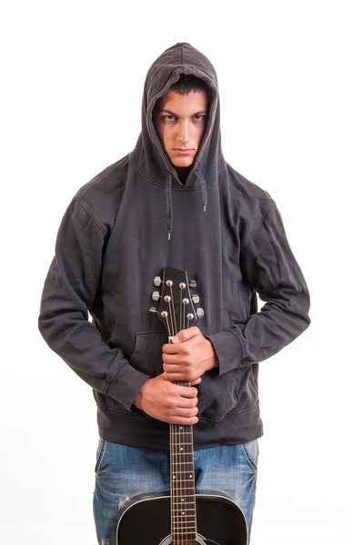 Un ragazzo con una felpa con cappuccio in piedi e con la chitarra in mano — Foto Stock