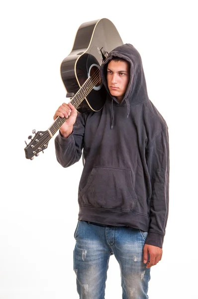 A young boy in hoodie standing with his guitar on the shoulder — Stock Photo, Image