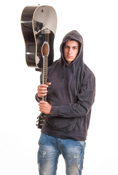 一个年轻的男孩在连帽衫站，抱着他的吉他 — 图库照片