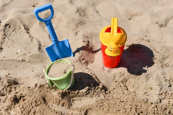 Coloridos juguetes de playa de verano, cubo, aspersor y pala en la arena — Foto de Stock