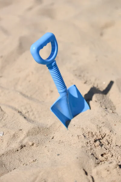 Pala de playa azul atascada en la arena por un niño — Foto de Stock